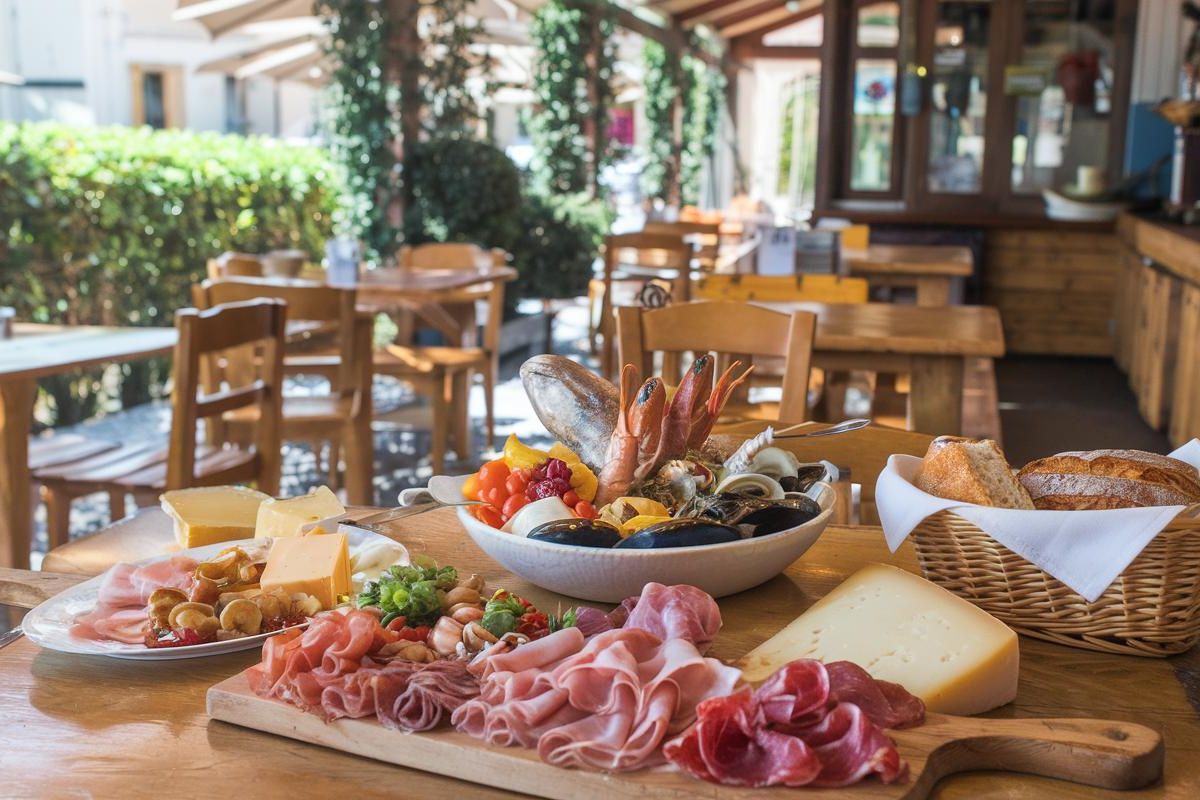 Try local goodies like charcuterie, cheeses, and seafood at a traditional cafe in Corsica, France before your cruise ship departs