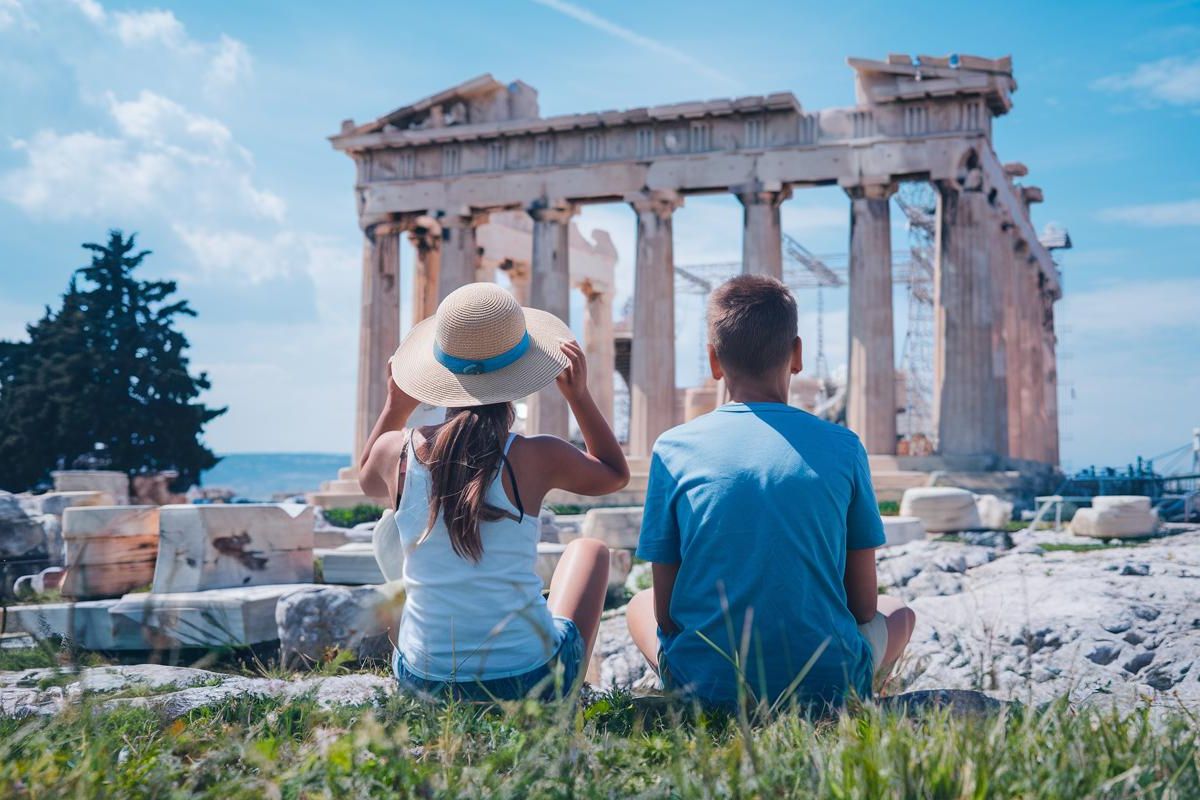 teen Girl. boy. Causal shorts, sun hat. sitting in front of the Parthenon, Greece