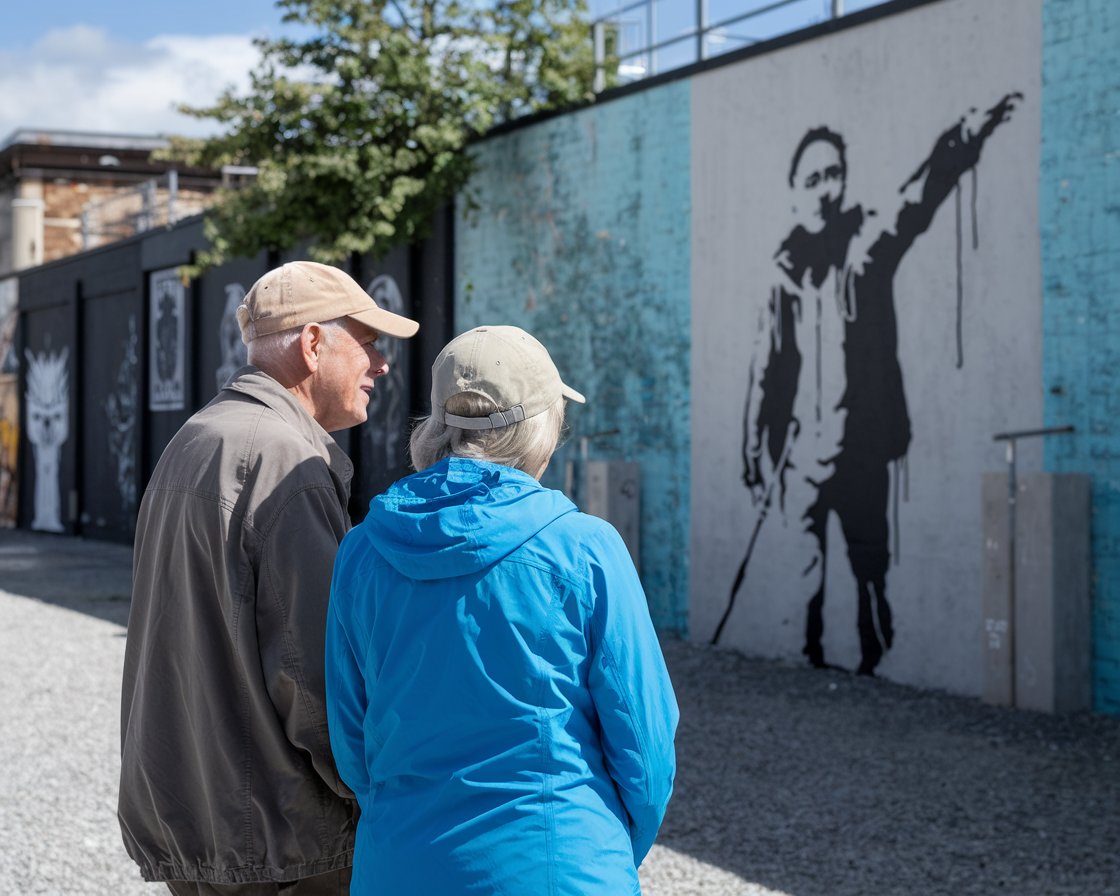 Older man and lady in walking shoes on a Banksy Street Art Tour on a sunny day