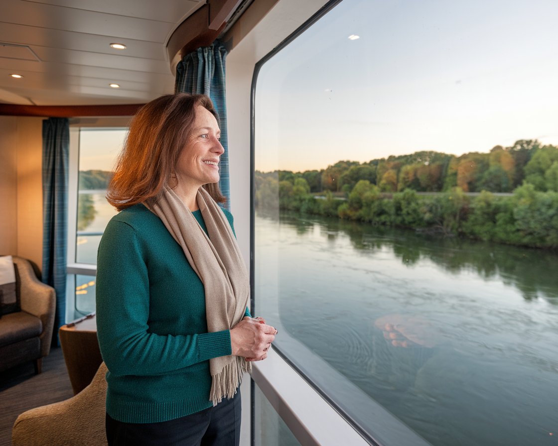 lady looking out the big floor to ceiling window in Cabin on a river cruise ship