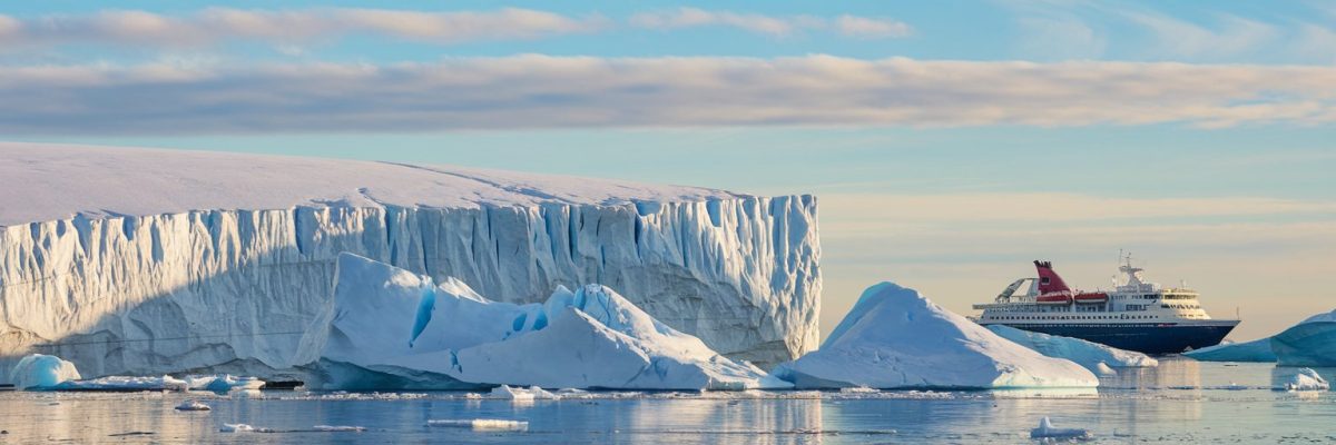 Massive ice sheet and giant icebergs in the polar regions with a cruise ship in the background