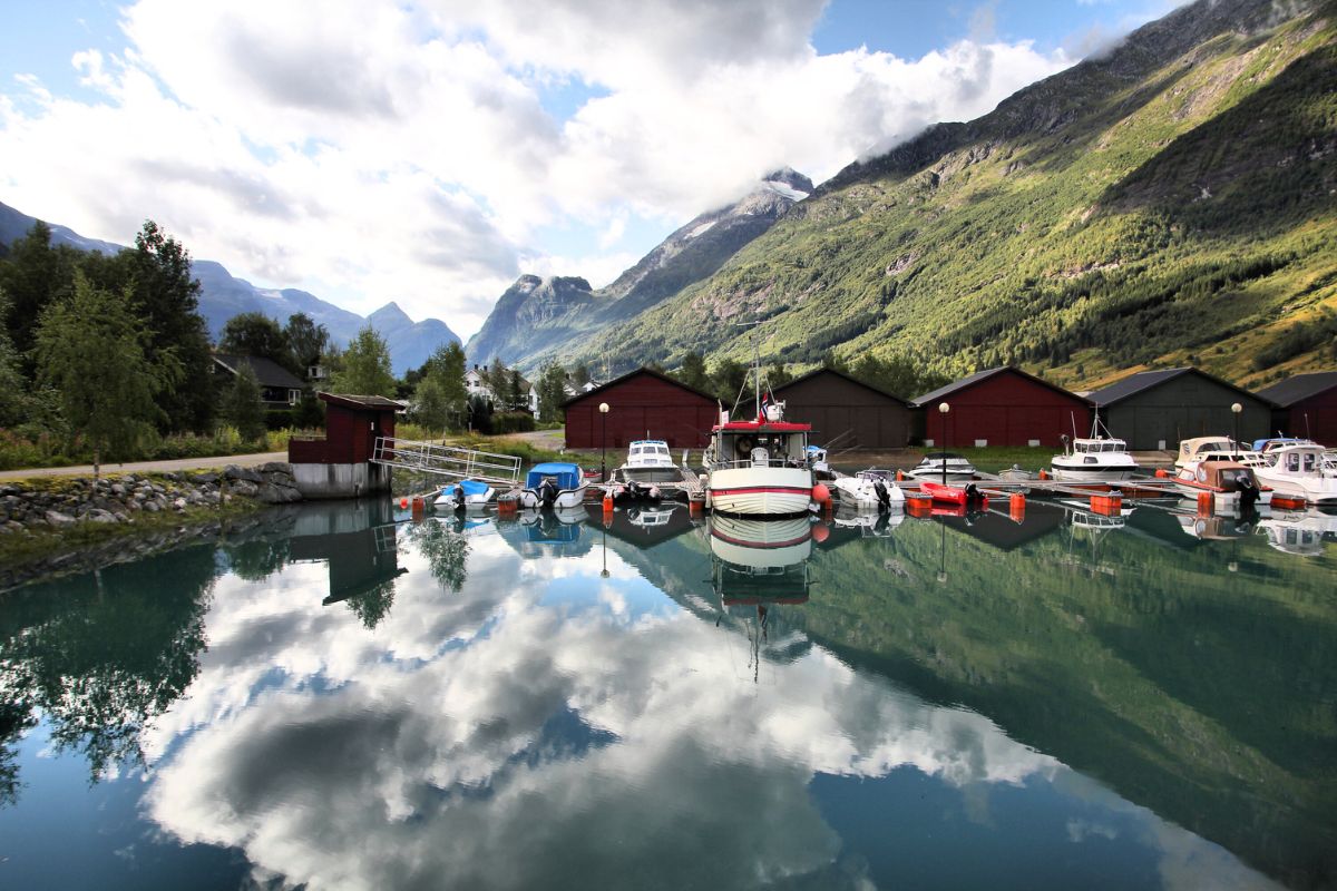 Olden Norway marina with boats moored in calm Nordfjord water reflecting mountains near cruise port