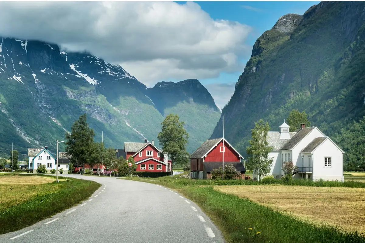 Olden Norway village with traditional red and white houses along road with dramatic fjord mountains