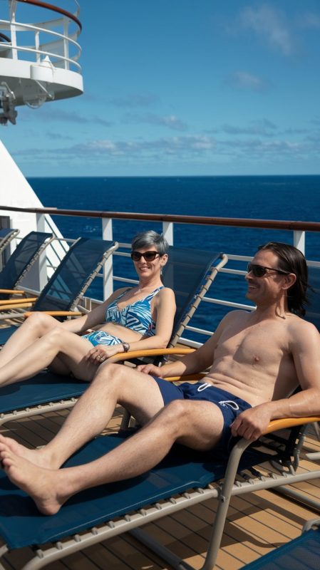 Mid aged lady and man on lounge chairs dressed in swimwear on a cruise ship. Sunny Day at Nice's cruise port.