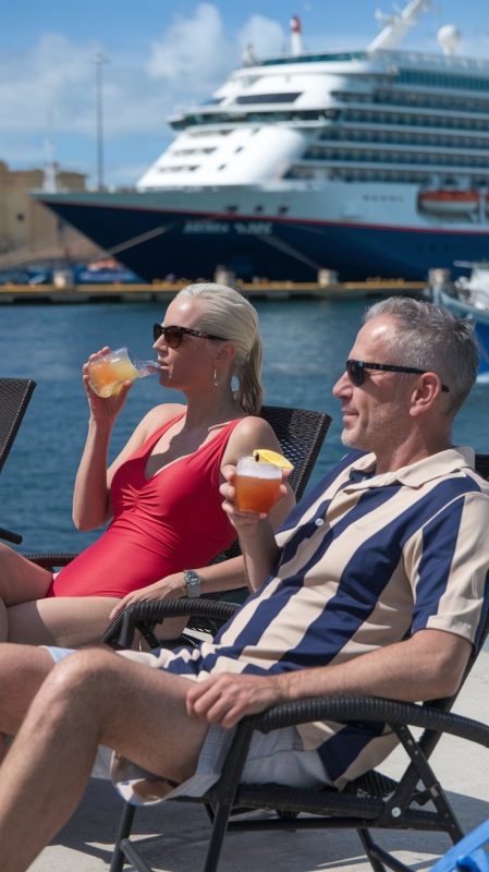 Mid aged lady and man on lounge chairs dressed in swimwear on a cruise ship. Sunny Day at Valletta Cruise Ship Port