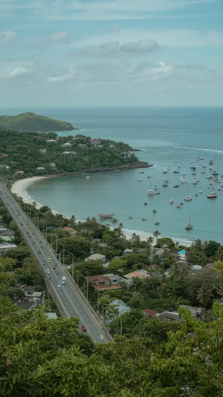 Distant cityscape with highway traffic, boats on the ocean horizon, tropical forest, taxi stand, remote beaches, rugged coastline, and scattered houses.