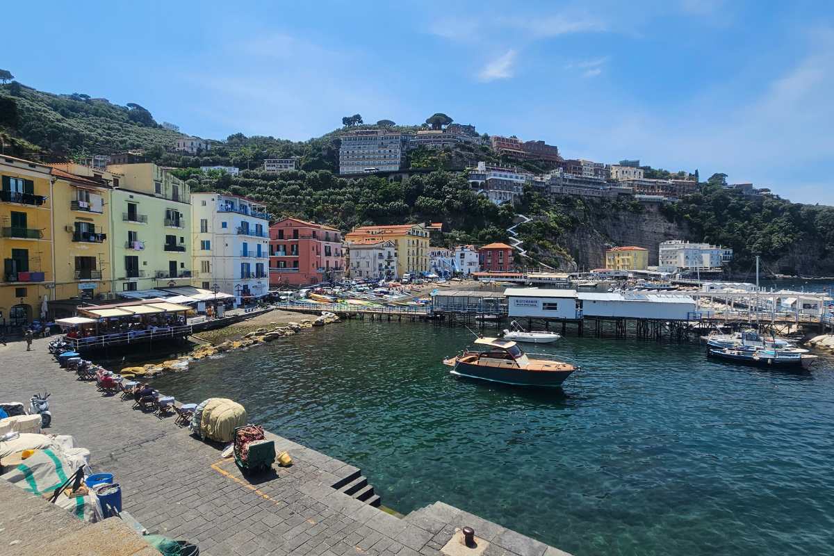 Marina Grande harbor in Sorrento with wooden fishing boats, colorful waterfront buildings, and clifftop town visible above
