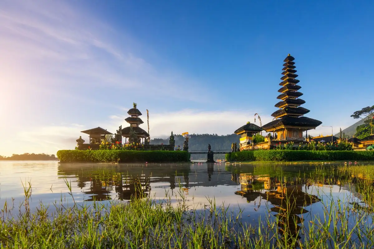 Balinese pagoda temple with multiple tiered roofs reflected in lake water at sunset