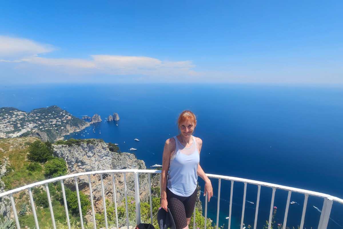 Sandra from About2Cruise at Monte Solaro viewpoint on Capri island with panoramic view of Faraglioni rock formations and deep blue Tyrrhenian Sea