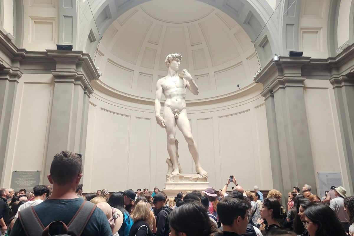 Michelangelo's David statue at Accademia Gallery in Florence with crowds of tourists viewing the famous Renaissance sculpture