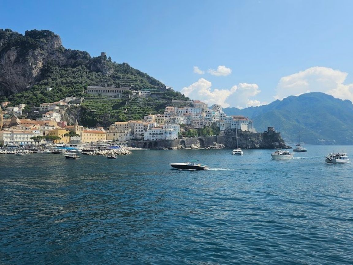 View of Amalfi town from the tender boat showing the harbour, cathedral bell tower and cliffside buildings