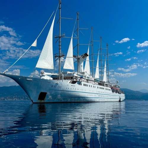 Elegant tall sailing ship with white sails on calm blue Mediterranean waters