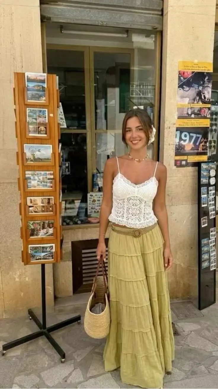 Woman in white lace corset top and sage tiered maxi skirt with raffia bag outside Rome shop