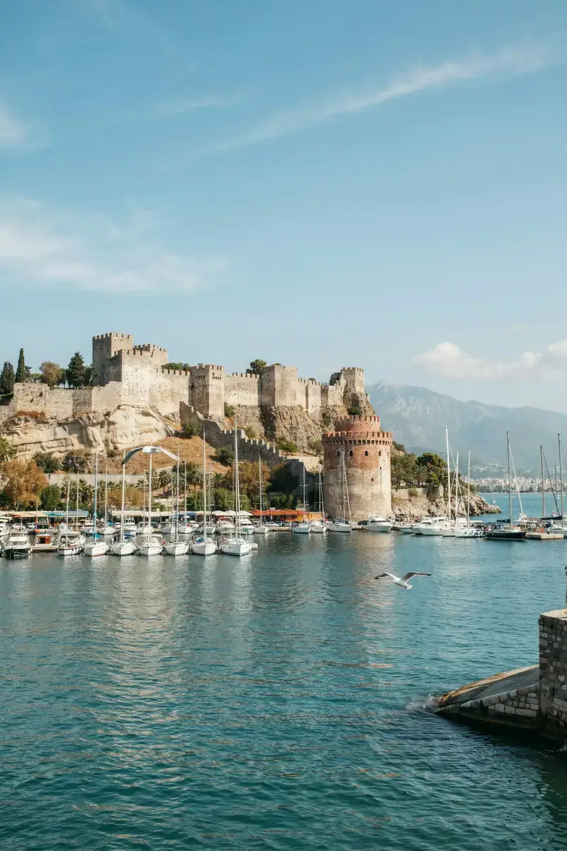 Alanya harbour with boats and a clifftop fortress overlooking the sea