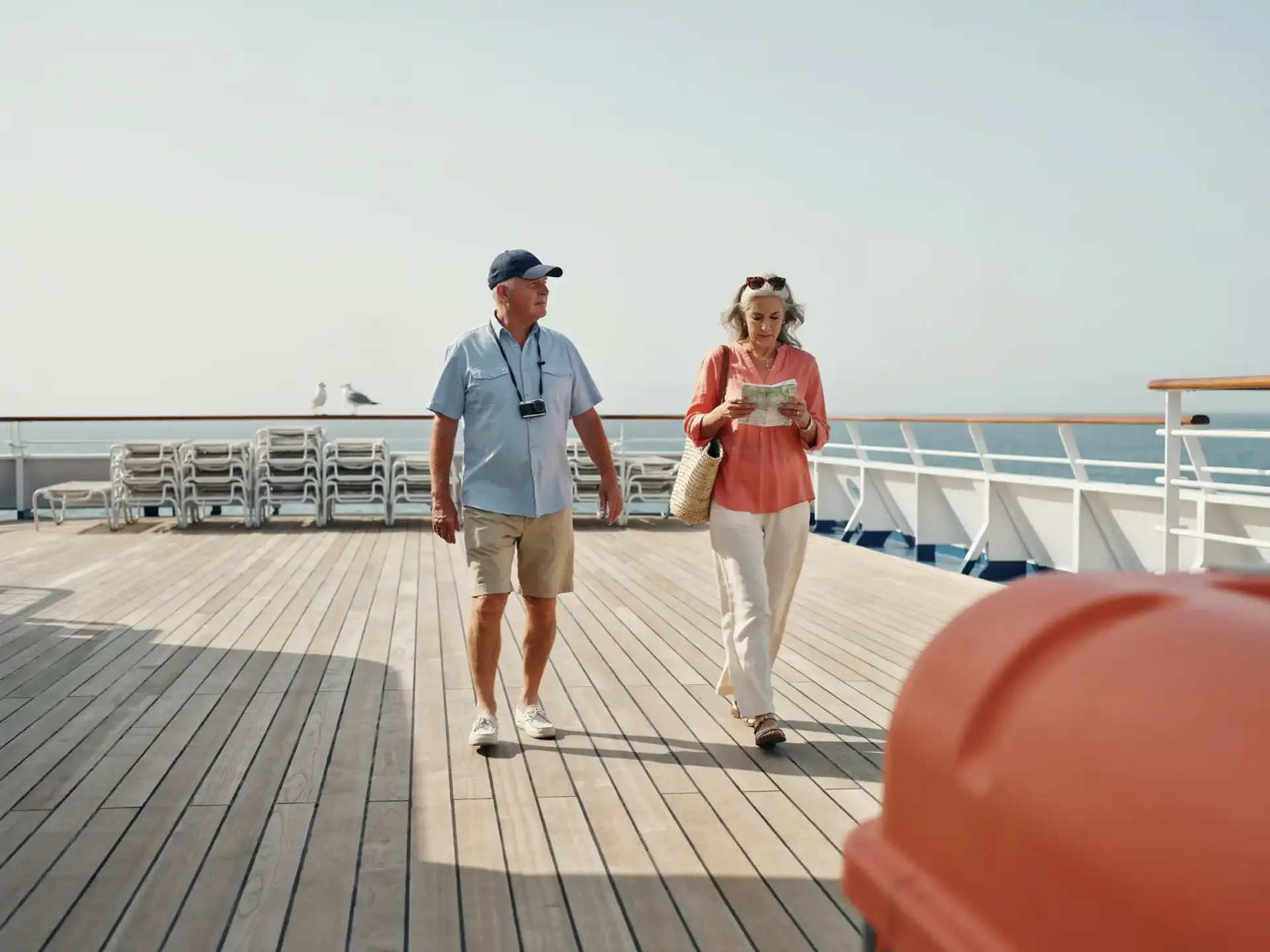 Group walking past a curved water slide on a bright ship deck