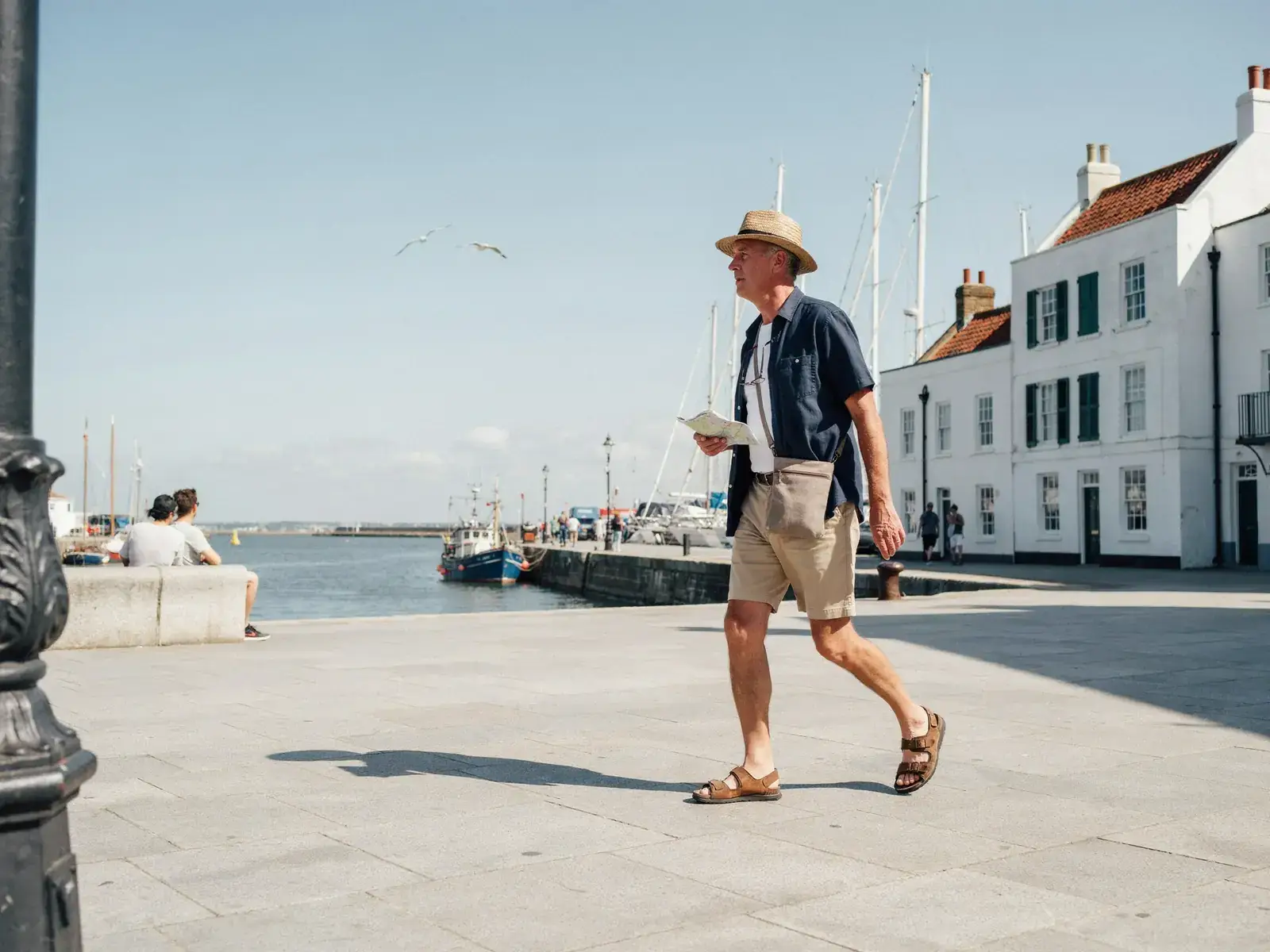 Older tourists strolling in bright sunshine, chatting as they make their way along a paved area