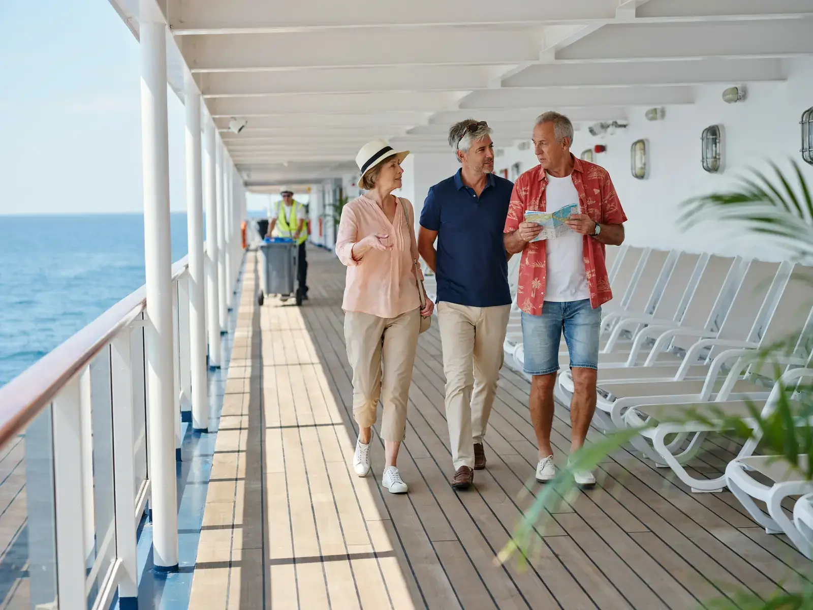 Older tourists strolling along a sunlit deck railing area