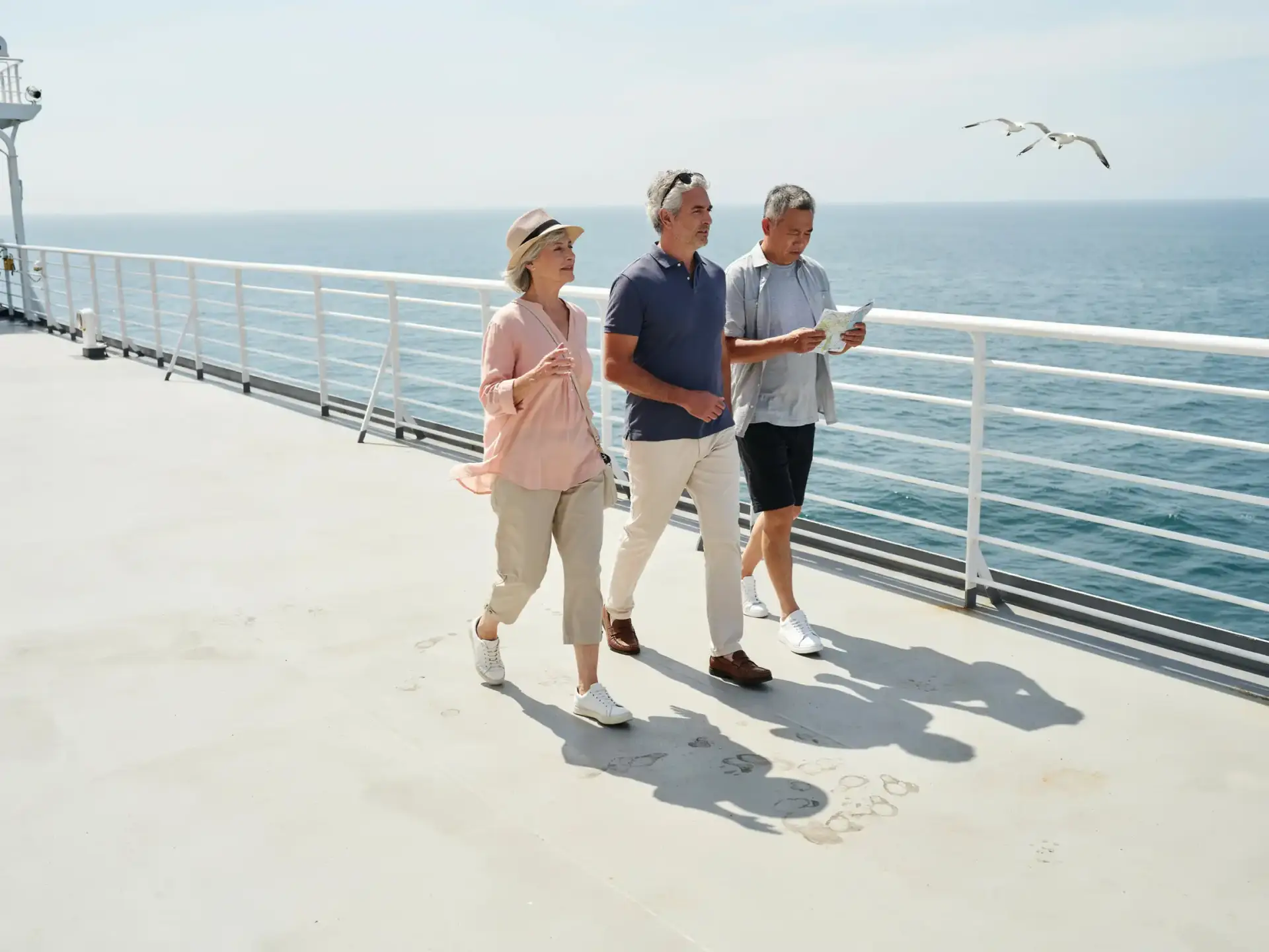 Older tourists strolling past deck railings in bright sunshine