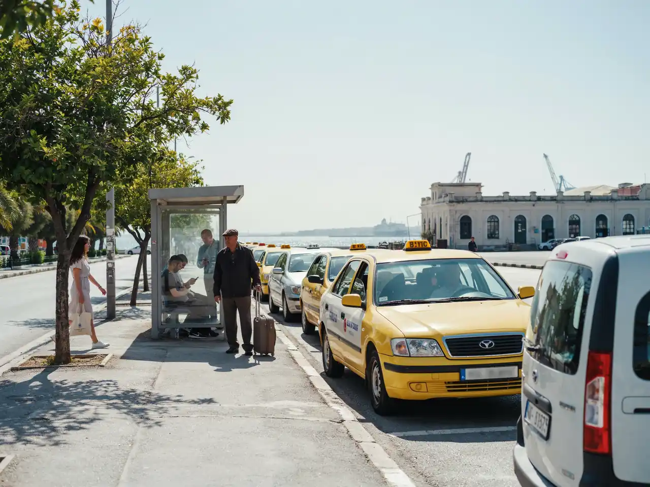Taxis and a bus waiting near the Izmir cruise port terminal on a sunny day