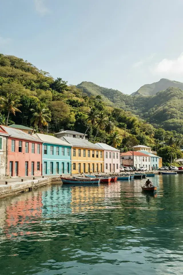Colourful waterfront buildings and green hills surrounding Kingstown harbour on a sunny day