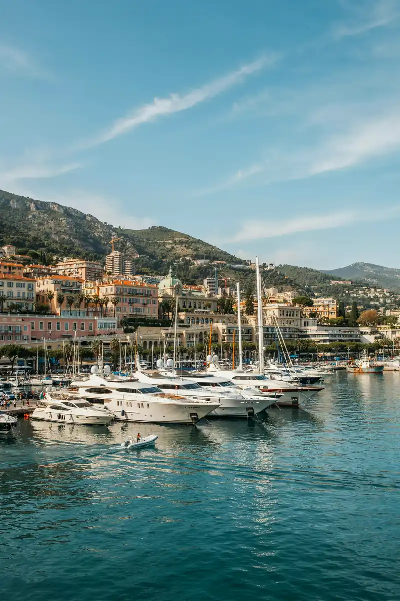 Monte Carlo harbour lined with yachts and a coastal skyline behind