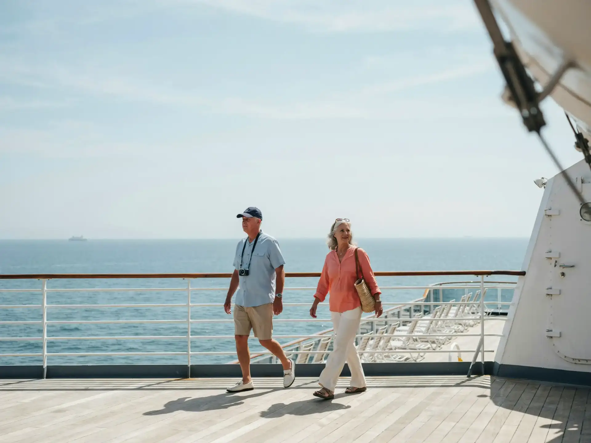 Older tourists strolling along a wide outdoor deck under a clear sky