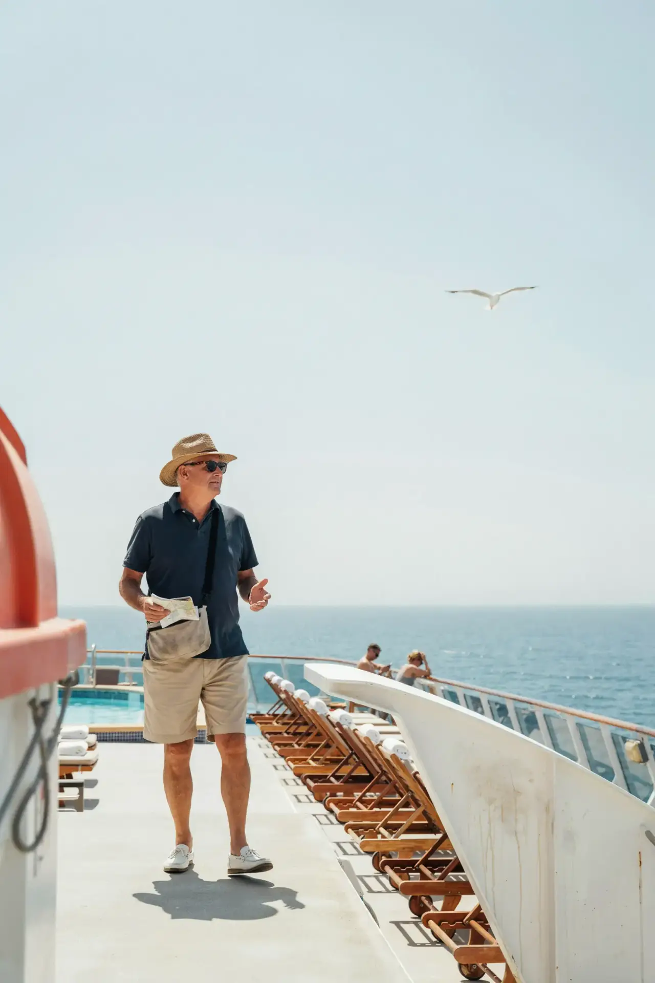 A group of older tourists walking together across a sunlit open deck