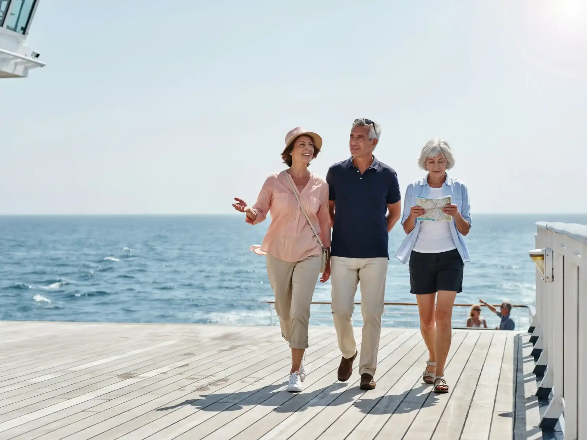 Group of older tourists chatting near a ship railing on a sunny day