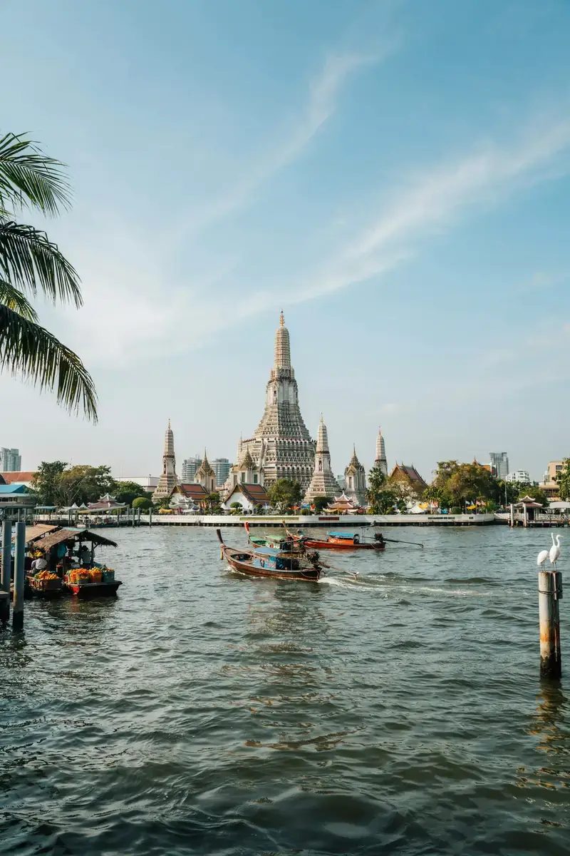 Bangkok riverside skyline with temples and boats along the water