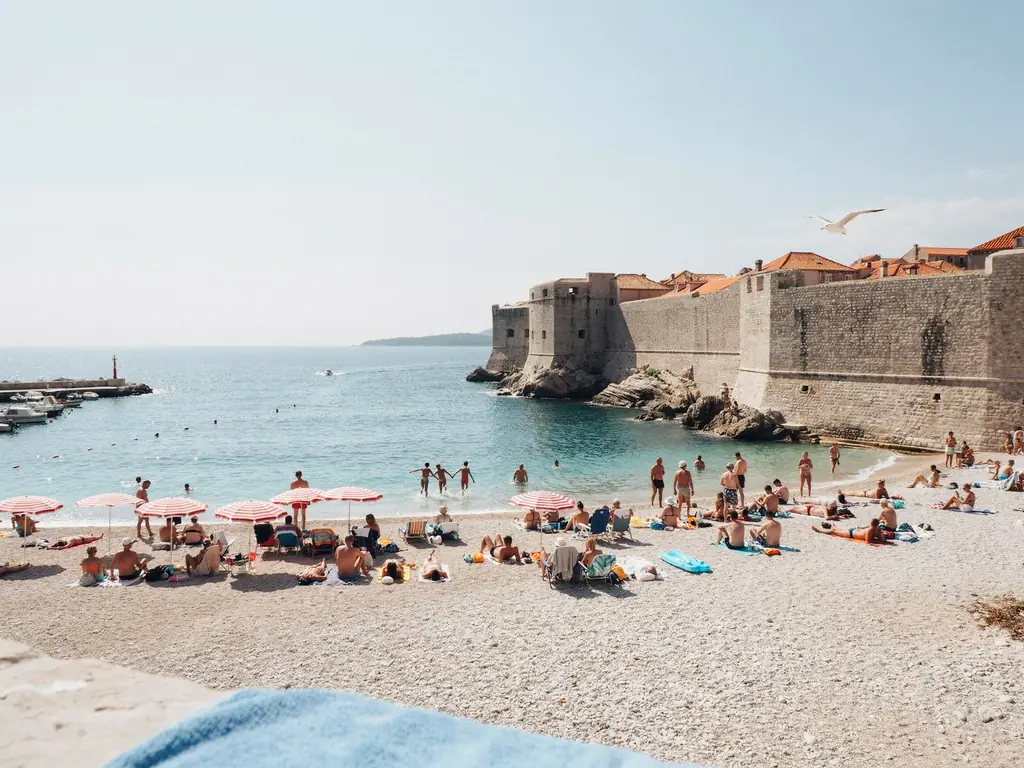 Banje Beach packed with sunbathers and swimmers near Dubrovnik's Old Town walls