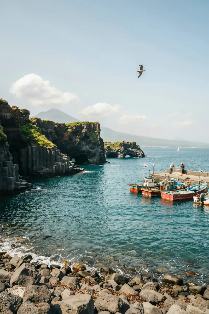 Volcanic cliffs and harbour along the Jeju Island coastline on a sunny day