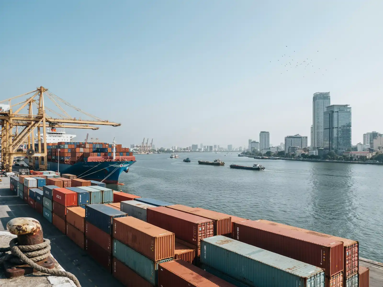 View contrasting Phu My port docks with the distant Ho Chi Minh City skyline on a sunny day