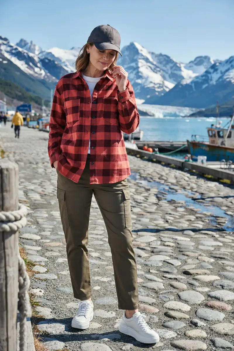 Woman in a red buffalo check flannel shirt and olive cargo trousers on an Alaska port street